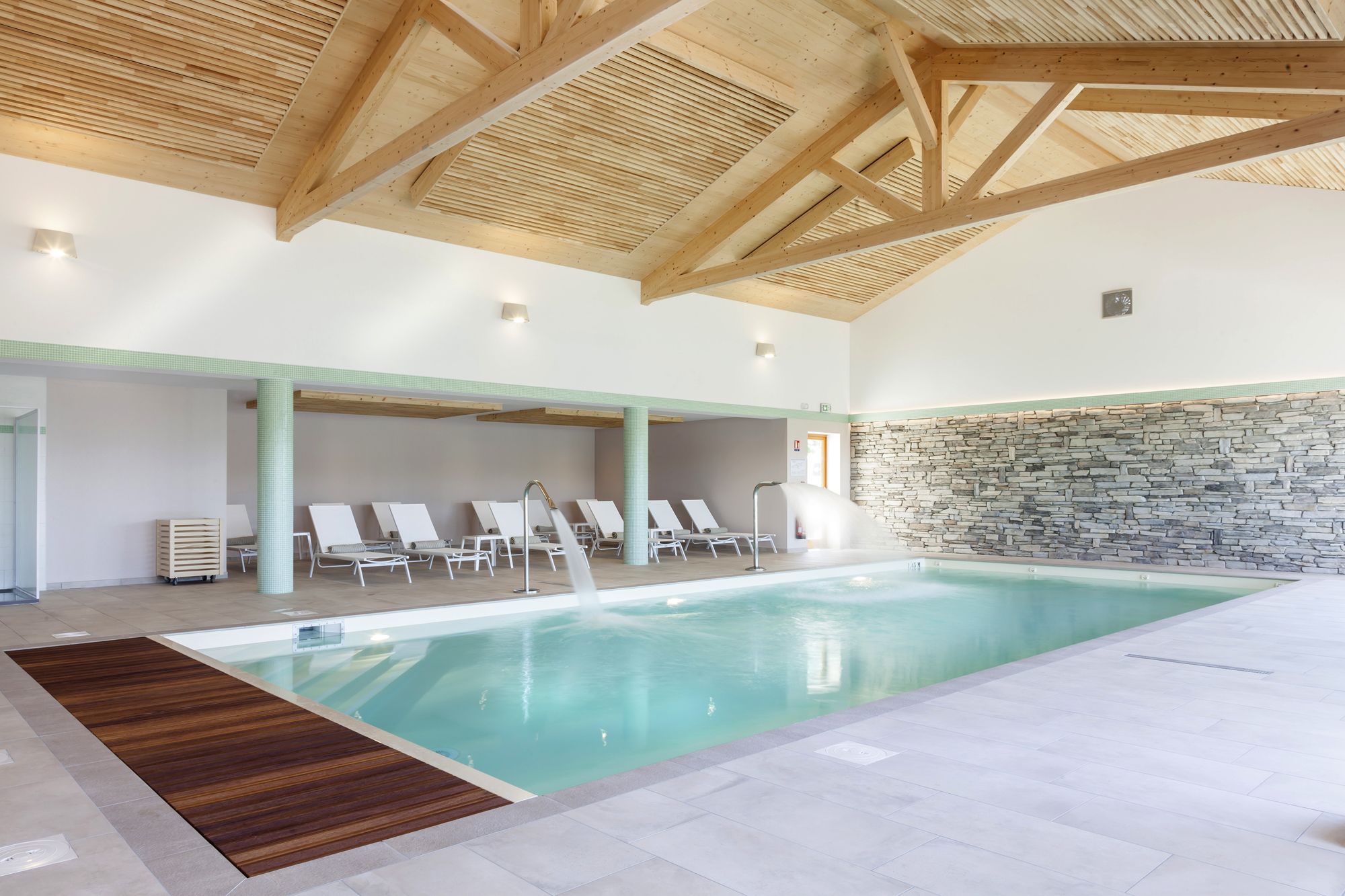 Una amplia piscina interior con vigas de madera y paredes de piedra.