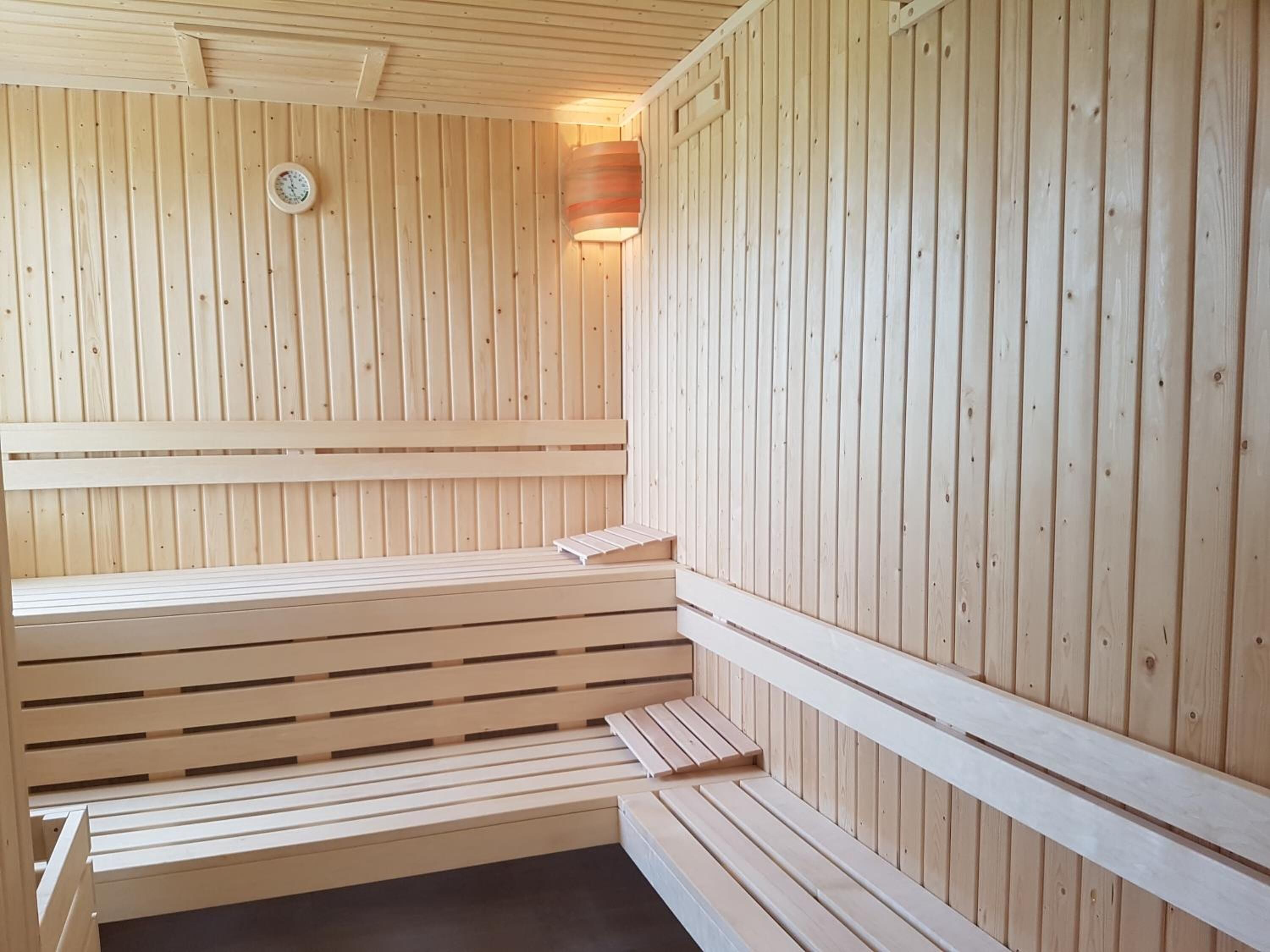 A sauna with wooden benches and a wall-mounted clock.
