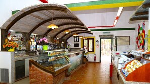A food court with a variety of food displays, a counter with a cash register, and a mural on the wall. - Eraclea Minoa Village (Cattolica Eraclea)