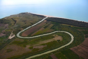 An aerial view of a winding river through a hilly landscape with fields and a distant shoreline. - Eraclea Minoa Village (Cattolica Eraclea)