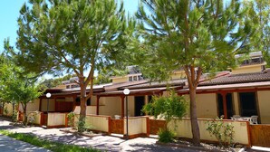 A traditional-style building with multiple rooms, a covered outdoor seating area, and a garden with pine trees. - Eraclea Minoa Village (Cattolica Eraclea)