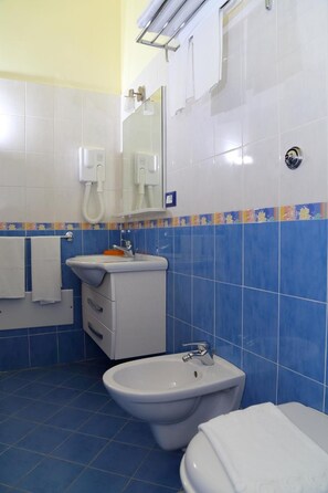 A bathroom with a toilet, bidet, and sink, featuring blue tiles and a mirror. - Eraclea Minoa Village (Cattolica Eraclea)