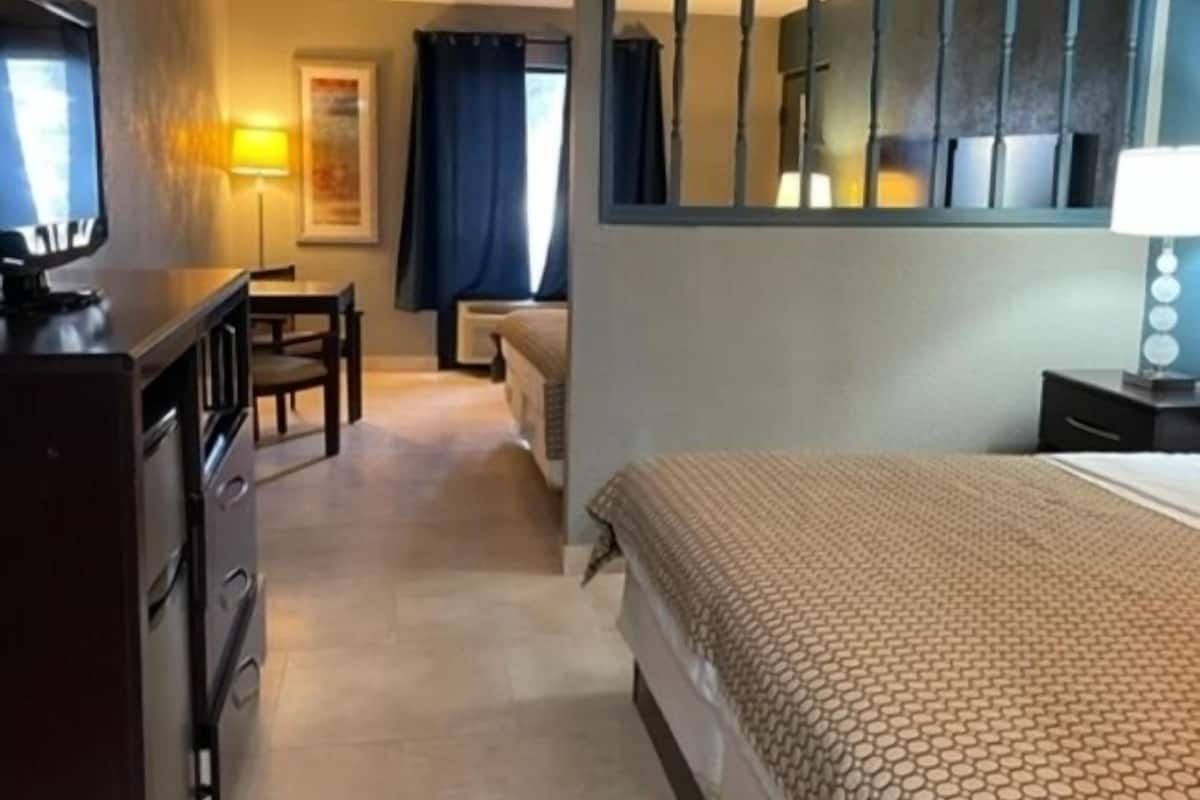 A hotel room with a bed, a desk, a chair, a television, and a window with curtains.