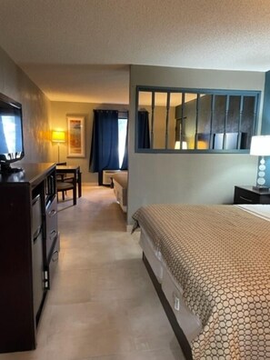 A hotel room with a bed, a desk, a chair, a television, and a window with curtains.
