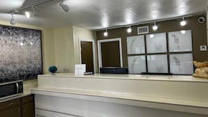Un área de recepción con mostrador, microondas y cuadros en la pared.