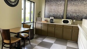 Una cocina con suelo a cuadros, un reloj, una cafetera y armarios.