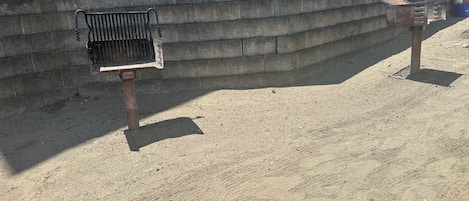 A concrete wall with a metal bench and a trash receptacle.