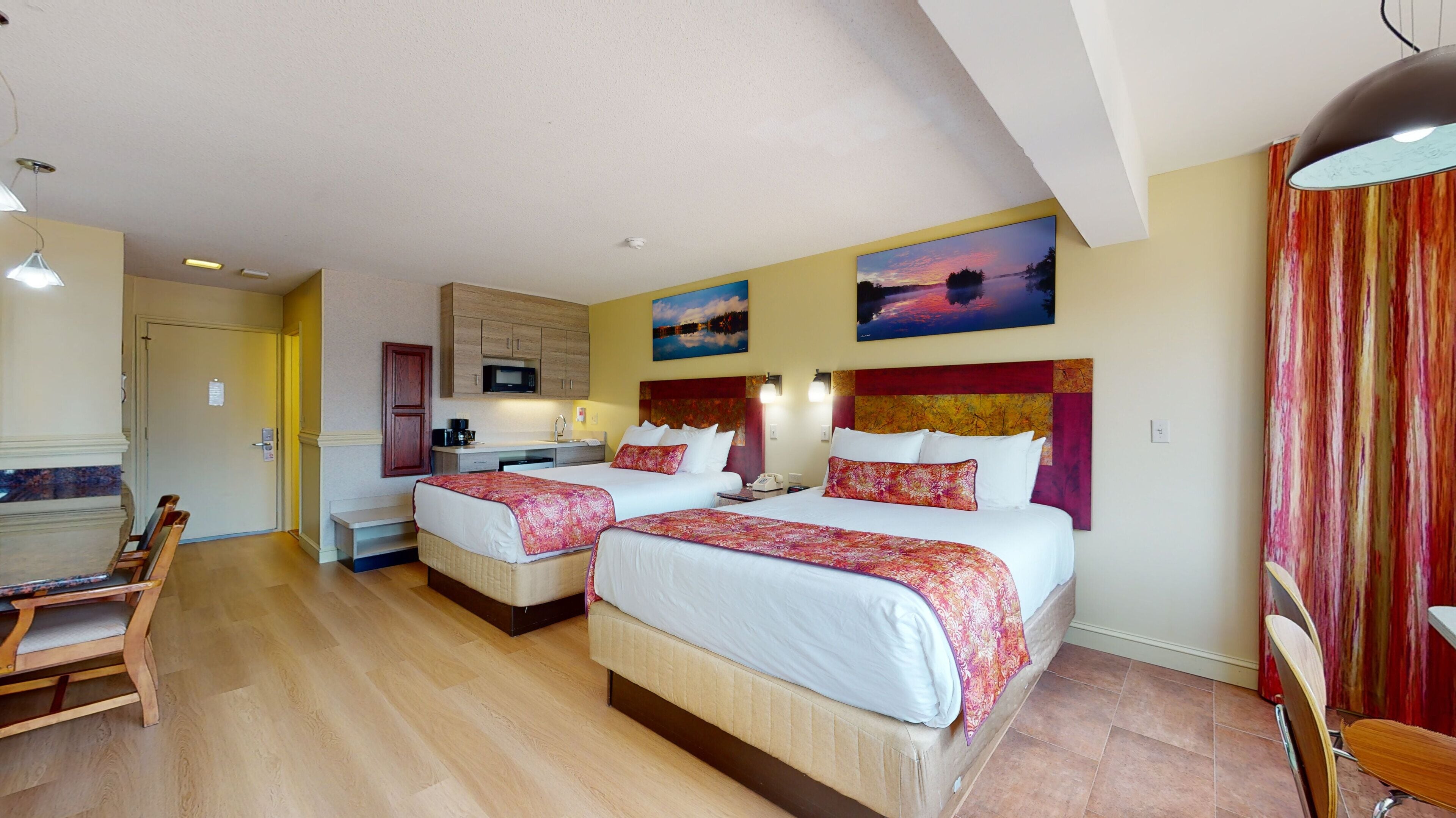 Une chambre d’hôtel avec deux lits, une kitchenette et un coin repas.
