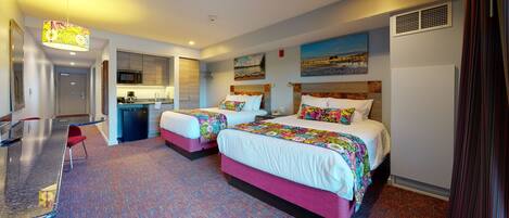 Une chambre d’hôtel avec deux lits, une kitchenette, une salle de bain et un petit coin salon.