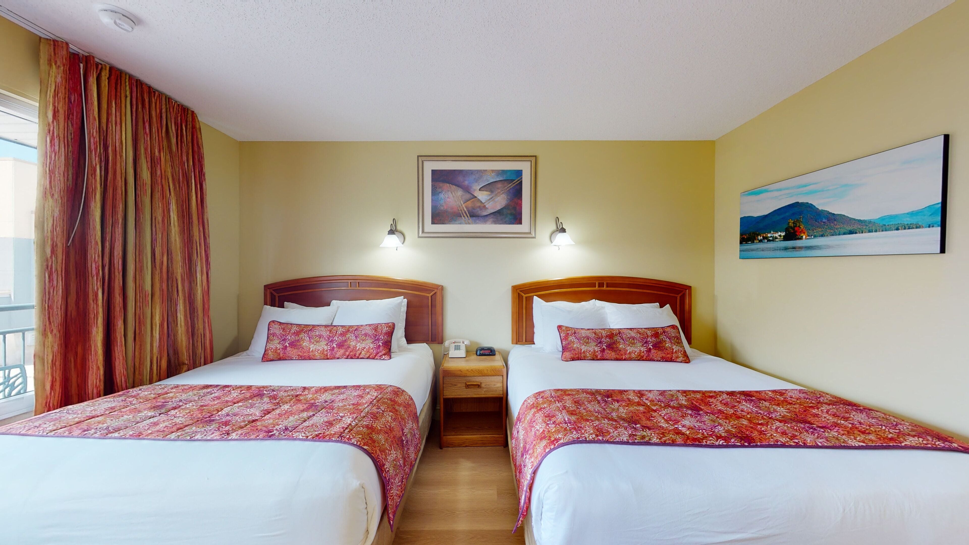 A hotel room with two beds, a nightstand, a painting, and a window with curtains.