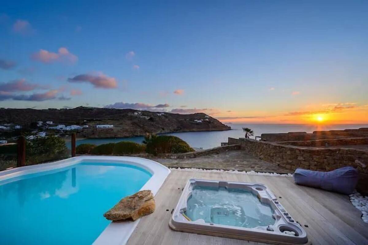 A pool with a hot tub and a sunset view.