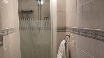 A small bathroom with a glass-enclosed shower, a toilet, and a towel rack.