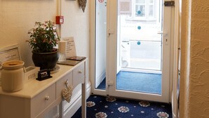 A hallway with a chandelier, a mirror, a door with a view, and a patterned carpet. - Bella Vista Lodge (Blackpool)