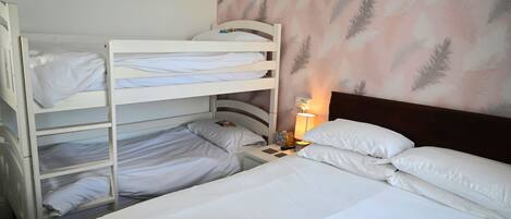 A hotel room with bunk beds, a bedside table with a lamp, and a feather-patterned wall.