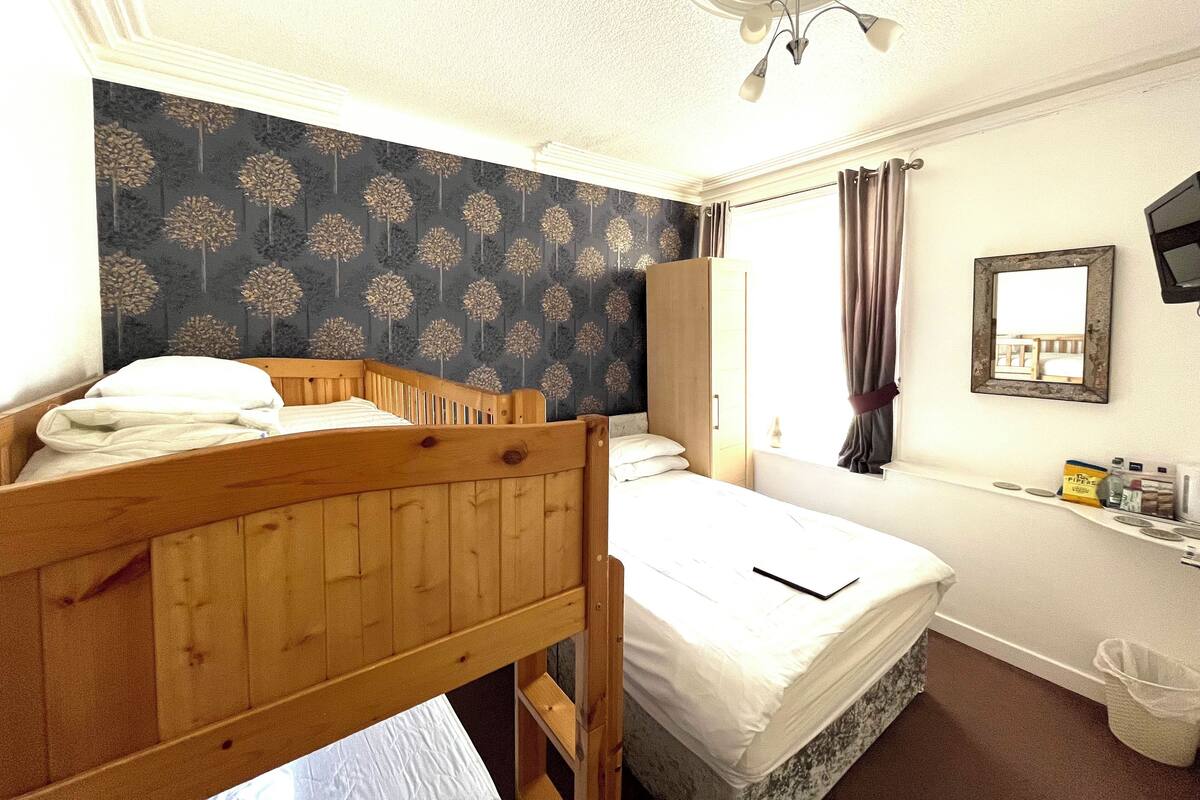A bedroom with a bunk bed, a wardrobe, a mirror, and a small desk with toiletries.