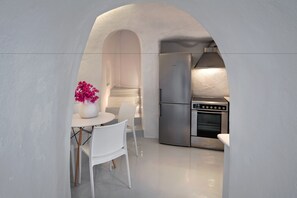A modern kitchen with stainless steel appliances, a white dining area with a vase of flowers, and an arched doorway.