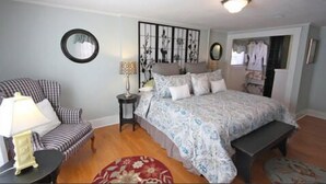 A bedroom with a bed, a chair, a lamp, and a mirror. - Inn at Park Spring (Portland)