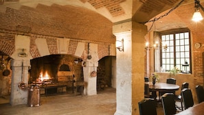 A rustic dining area with brick walls, a fireplace, and a table set for dining. - Château de Bonnemare (Radepont)