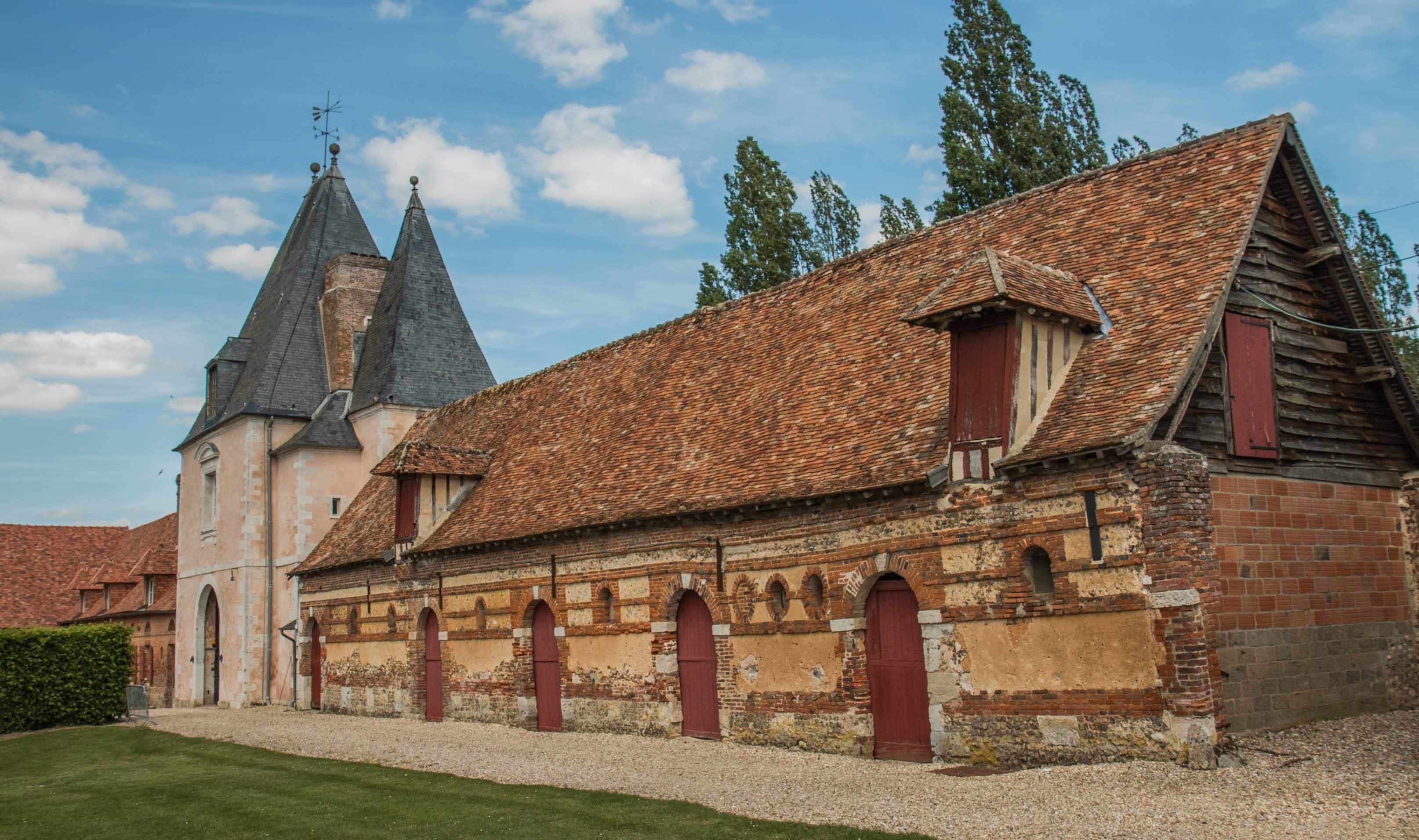 Un bâtiment historique doté d’un toit en tuiles, de fenêtres en arc de cercle et d’une façade en briques.