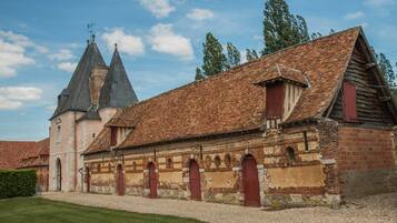 Un bâtiment historique doté d’un toit en tuiles, de fenêtres en arc de cercle et d’une façade en briques.
