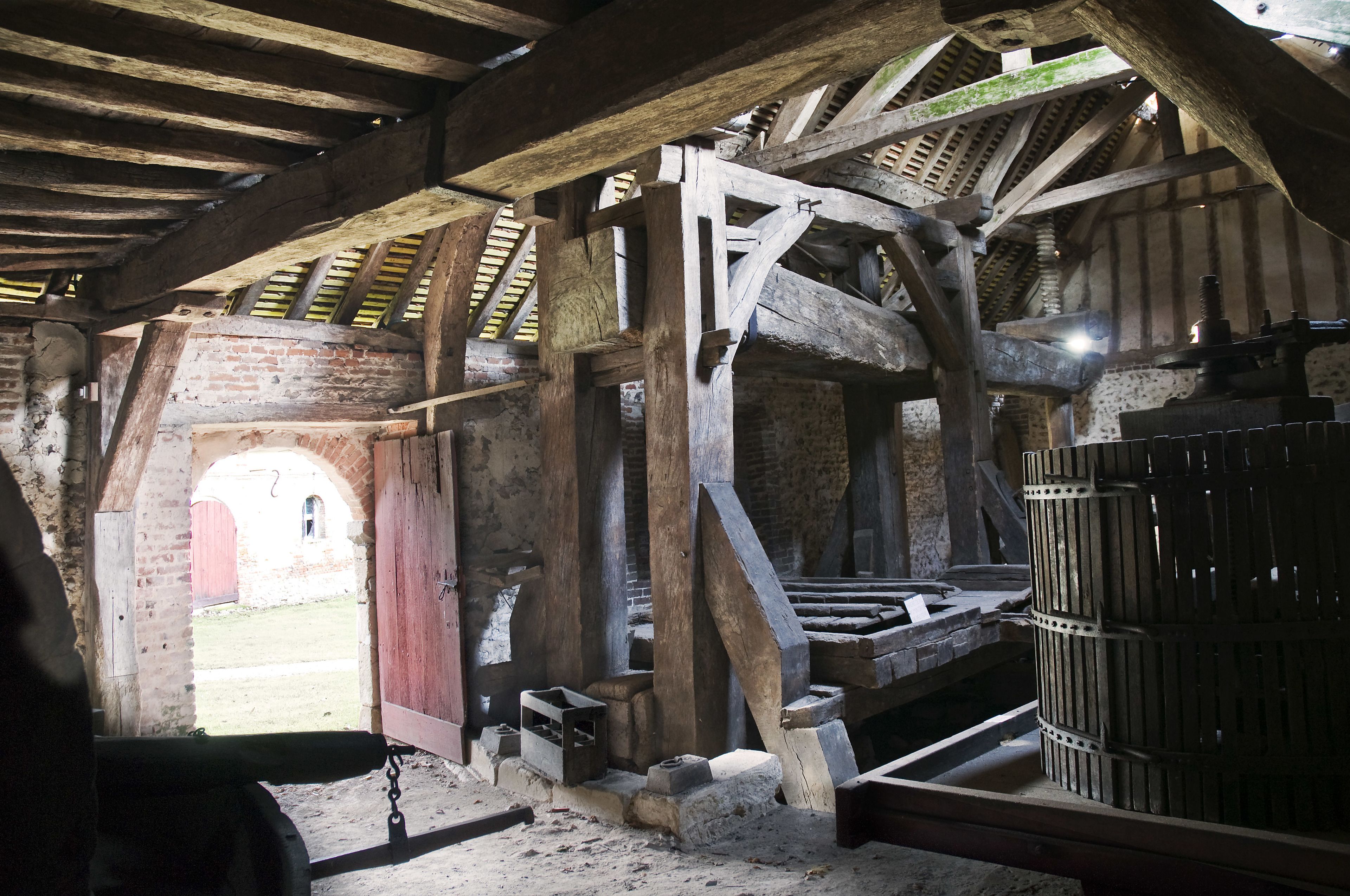 An interior with exposed wooden beams, brick walls, and a metal gate.