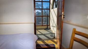 Una habitación pequeña con una cama, una silla y una ventana.