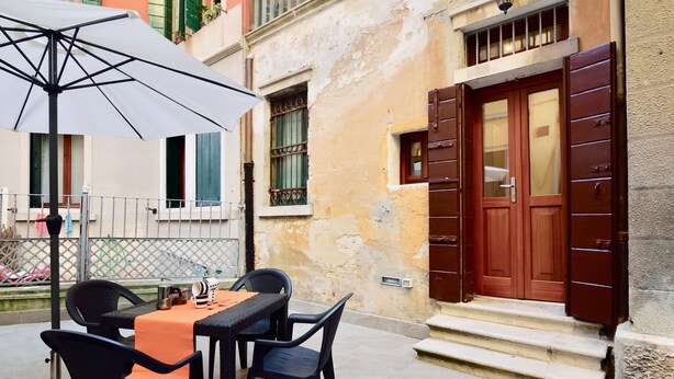 An outdoor seating area with a table, chairs, and an umbrella. - Ca' Etta (Venice)