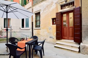 An outdoor seating area with a table, chairs, and an umbrella. - Ca' Etta (Venice)