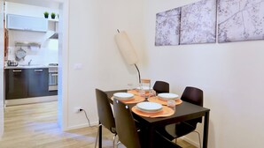 A dining area with a table set for four, surrounded by chairs, and a kitchen in the background. - Ca' Etta (Venice)