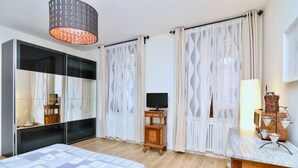 A bedroom with a bed, a TV, a wooden side table, a lamp, and a dresser. - Ca' Etta (Venice)