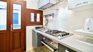 A compact kitchen with wooden cabinets, a gas stove, and a dishwasher. - Ca' Etta (Venice)