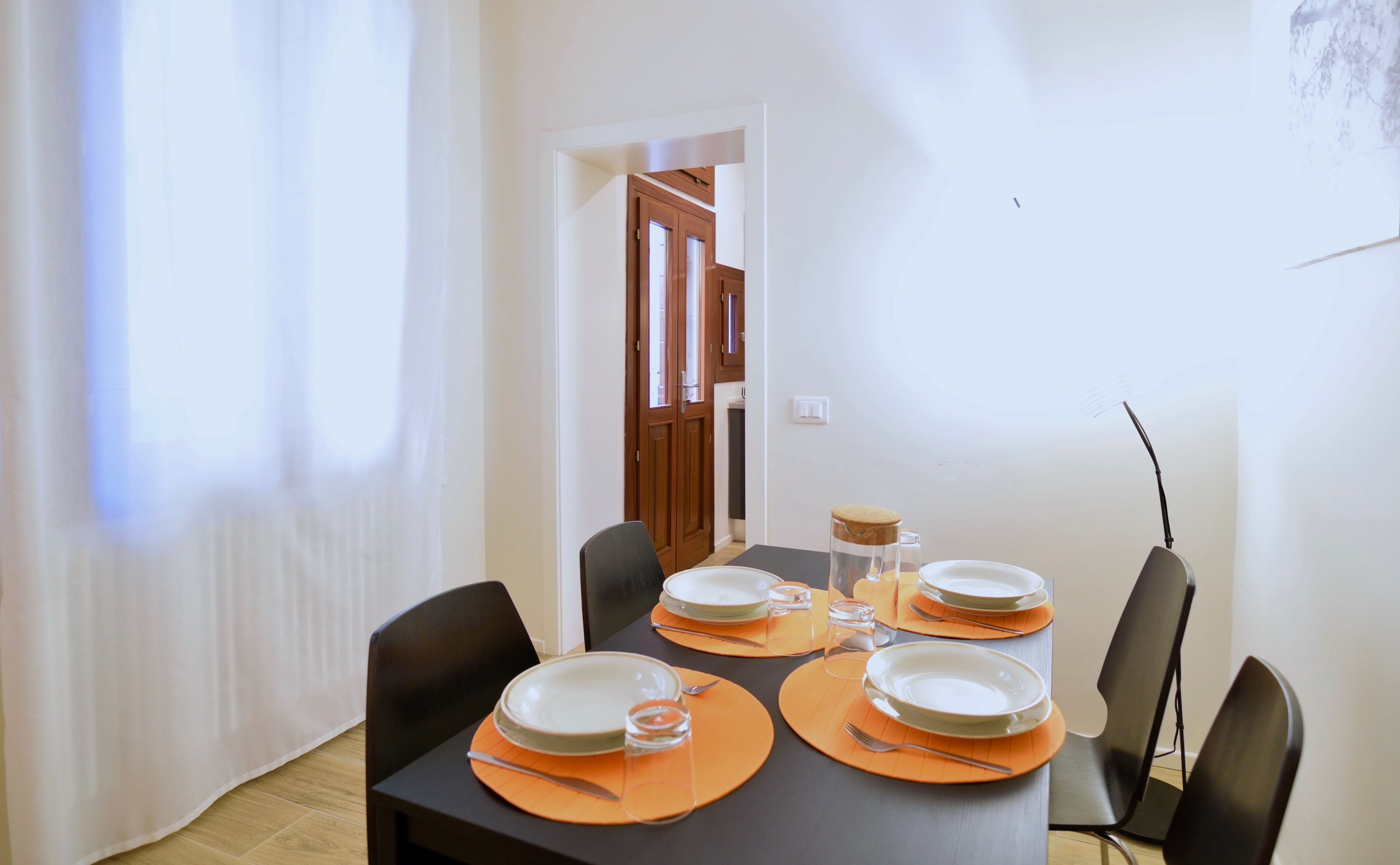 A dining area with a table set for four, including plates, cutlery, and glasses.