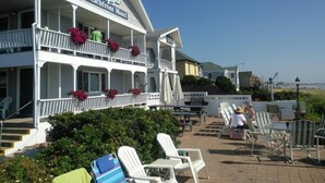 Ein Motel direkt am Strand, mit einem zweistöckigen Gebäude, Sitzbereich im Freien mit Stühlen und Tischen und freiem Blick auf den Strand.