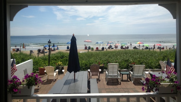 Eine überdachte Terrasse mit Sitzmöbeln und Blick auf den Strand.