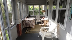 Ein überdachter Balkon mit Tisch, Stühlen und Teppich, an einer Ziegelwand.