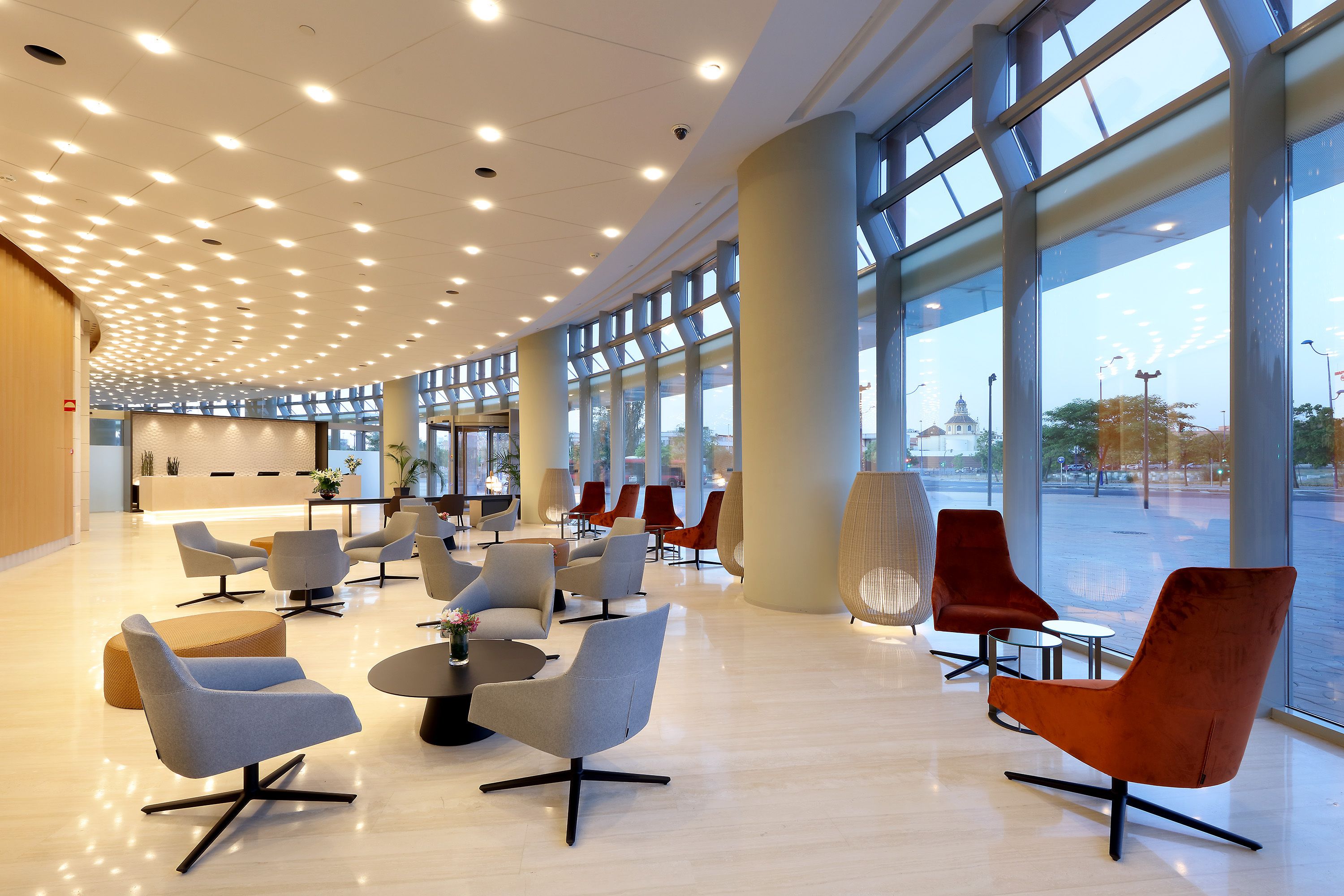 A spacious lobby with modern seating, large windows, and a curved ceiling with recessed lighting.