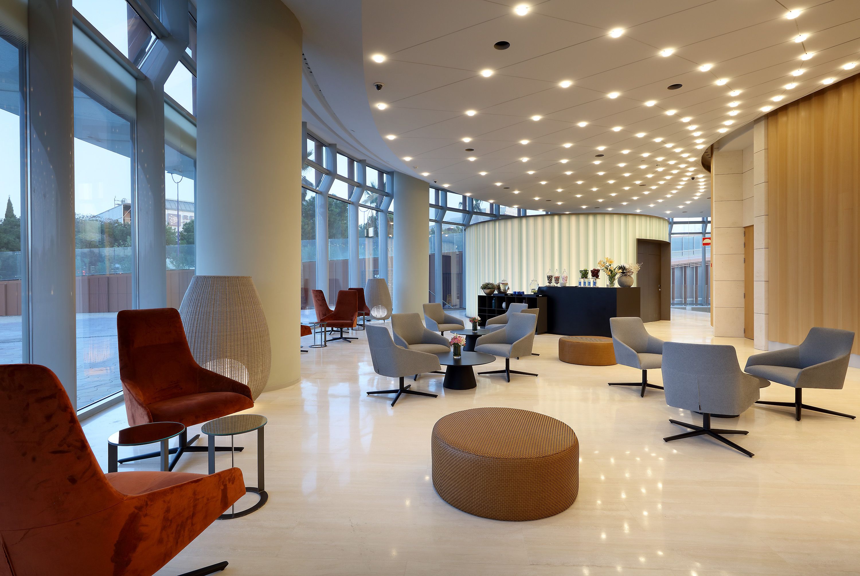 Un hall amplio con mobiliario moderno, ventanas grandes y una recepción central.