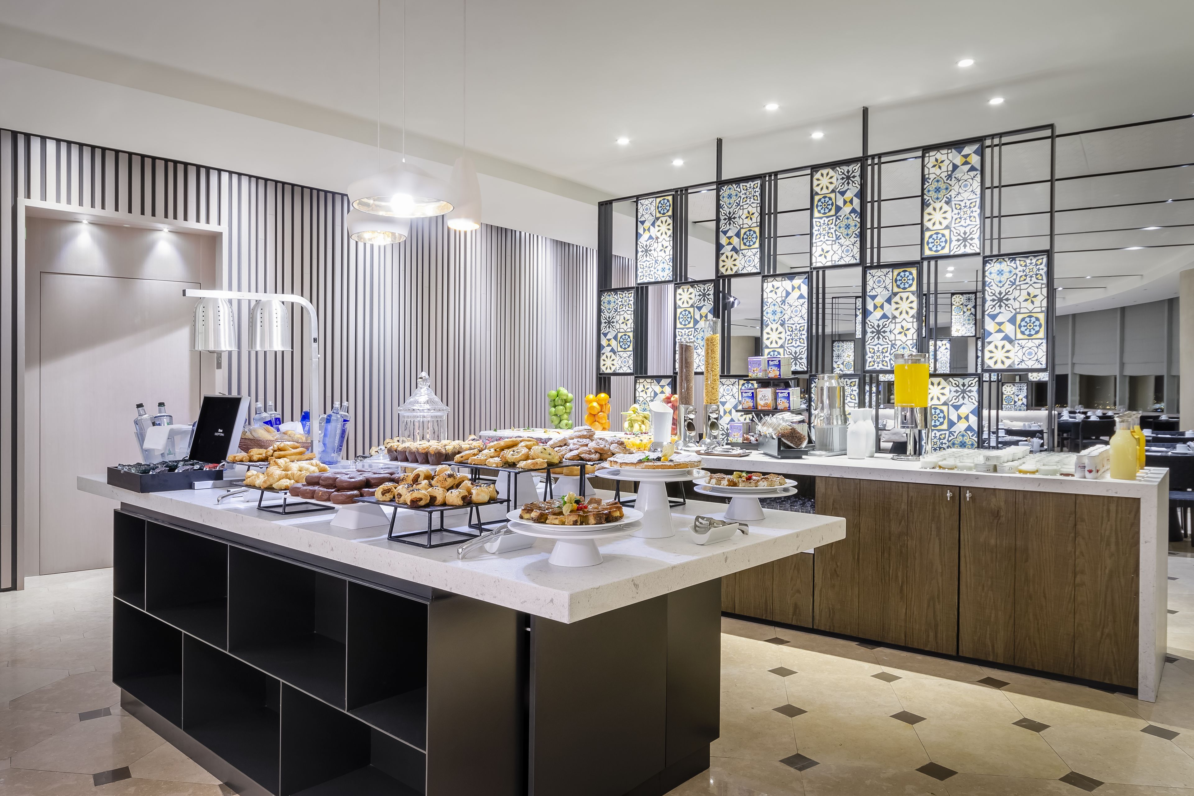 A buffet setup with various food items and a modern kitchen area in the background.