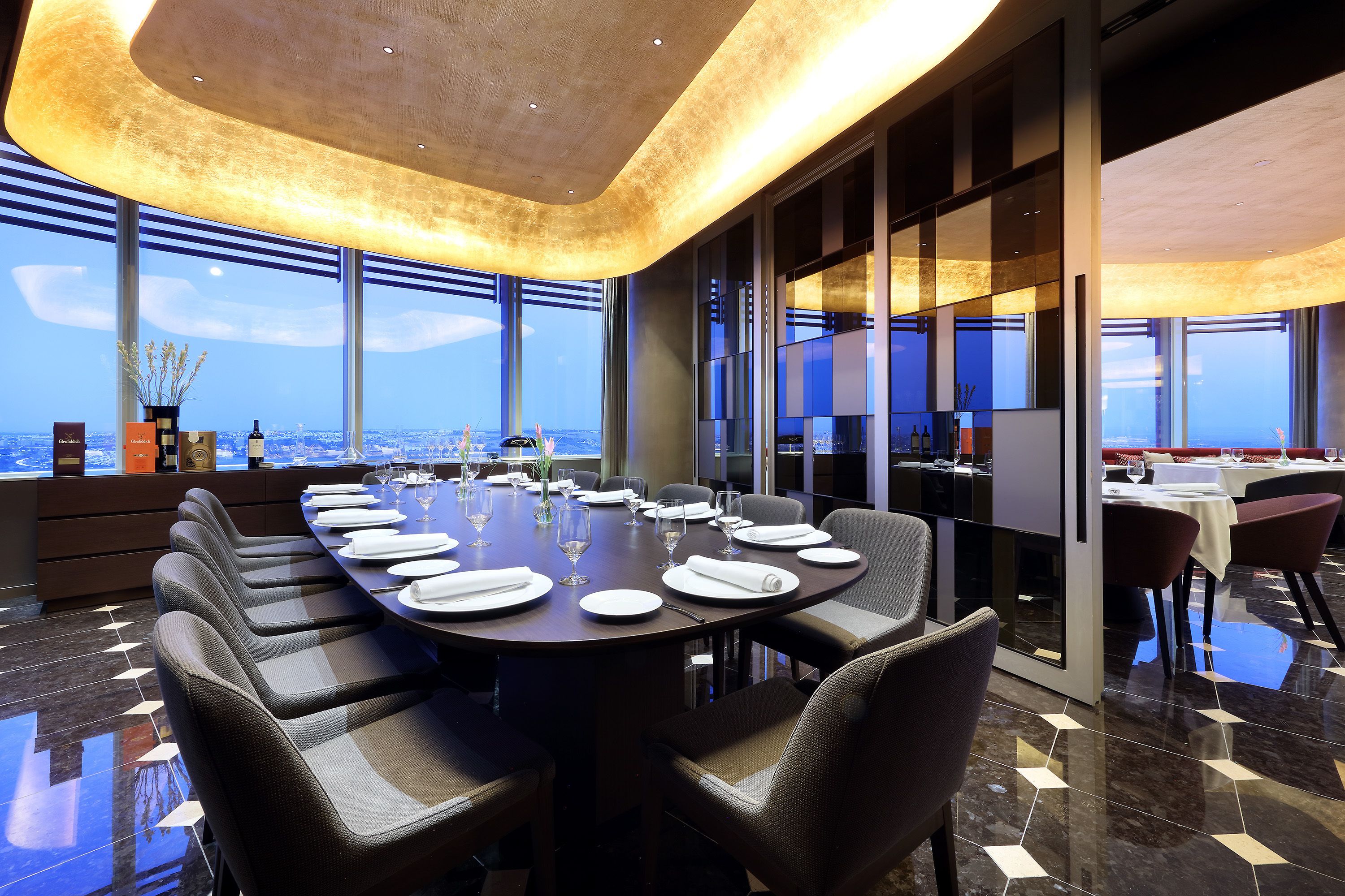 Una sala de conferencias moderna con vistas panorámicas de la ciudad, una larga mesa dispuesta para una reunión y un diseño de interiores sofisticado.