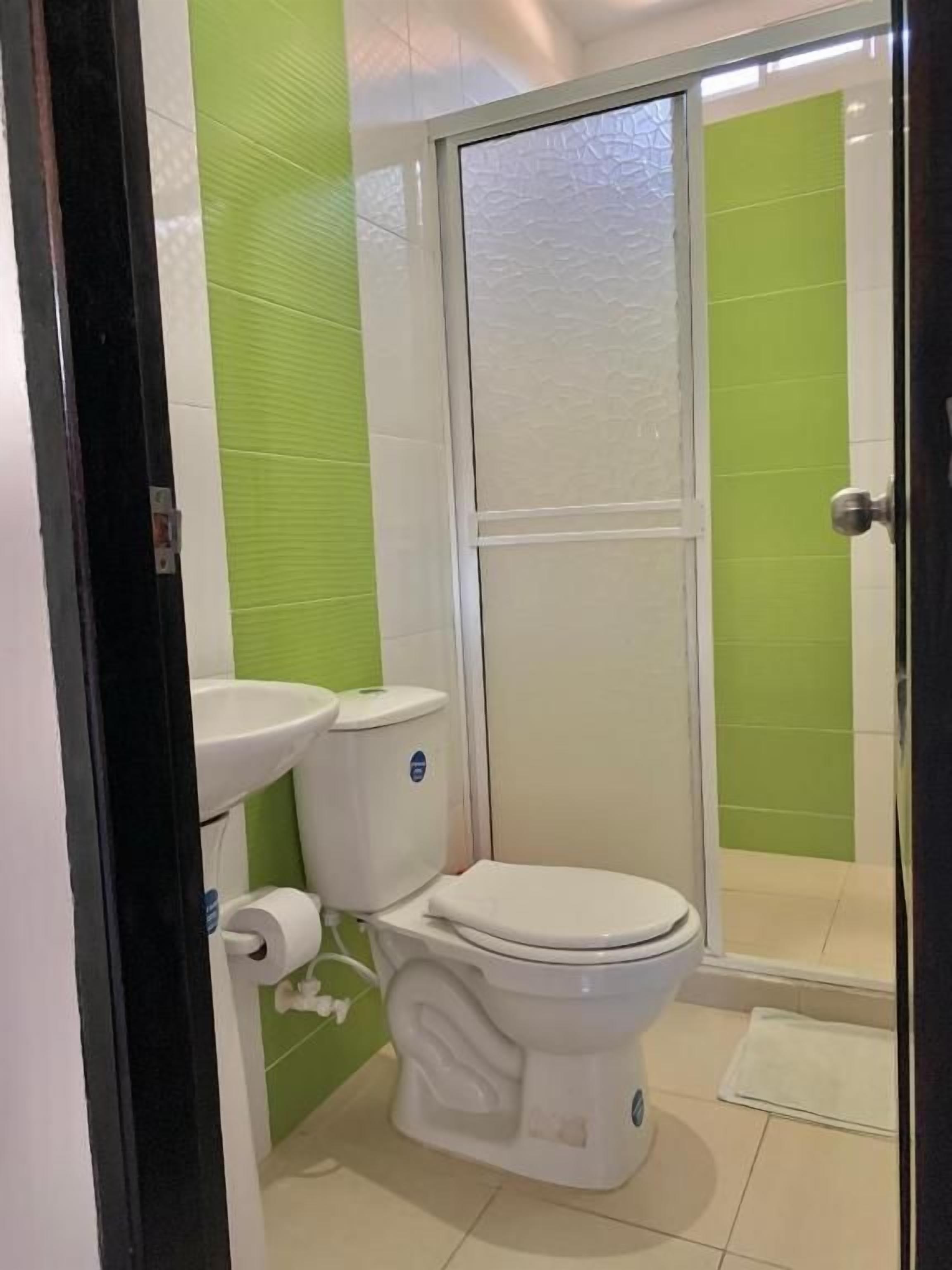 A bathroom with a toilet, sink, and shower area.