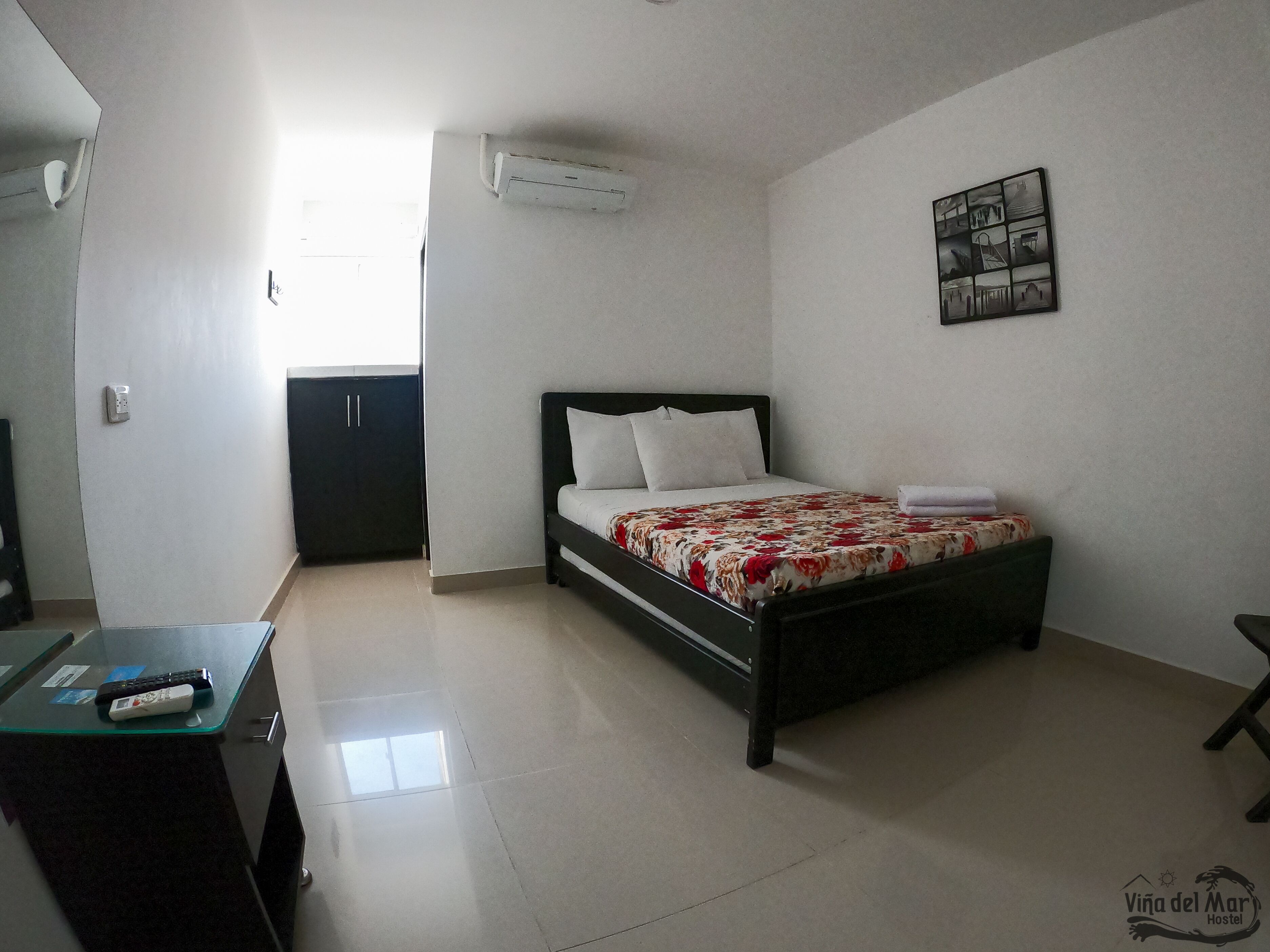 Un dormitorio con cama, escritorio y aire acondicionado.