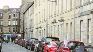 A row of parked cars along a cobblestone street in front of a building with multiple windows and a sign for a veterinary surgery. - Edinburgh City Retreat Apartments (Edinburgh)