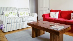 A living room with a striped sofa, a red sofa, and a wooden coffee table. - Edinburgh City Retreat Apartments (Edinburgh)