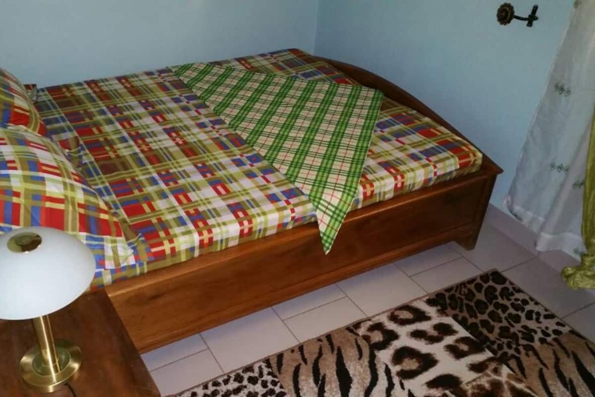 A bed with a colorful quilt, a wooden headboard, and a bedside lamp.