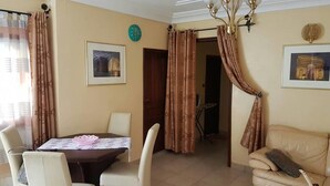 A living room with a dining table, chairs, a sofa, and a chandelier. - Bs VIP Appartement (Yaoundé)