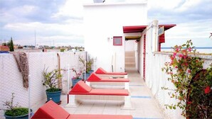 A corridor with red benches, potted plants, and a view of the sea.