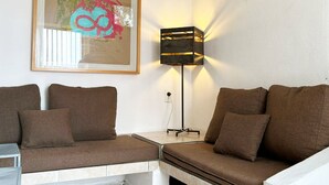A modern living room with a brown sofa set, a framed abstract painting, and a floor lamp.