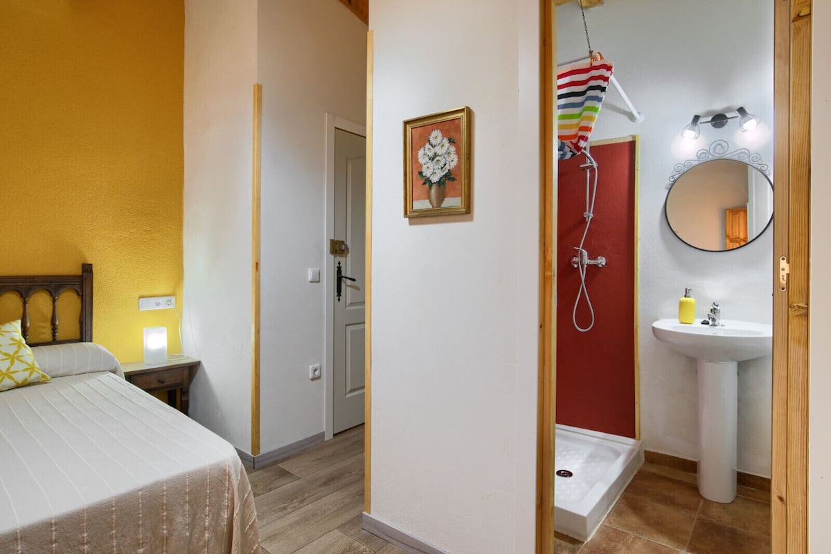 Ein Hotelzimmer mit Bett, Dusche, Waschbecken und Spiegel.