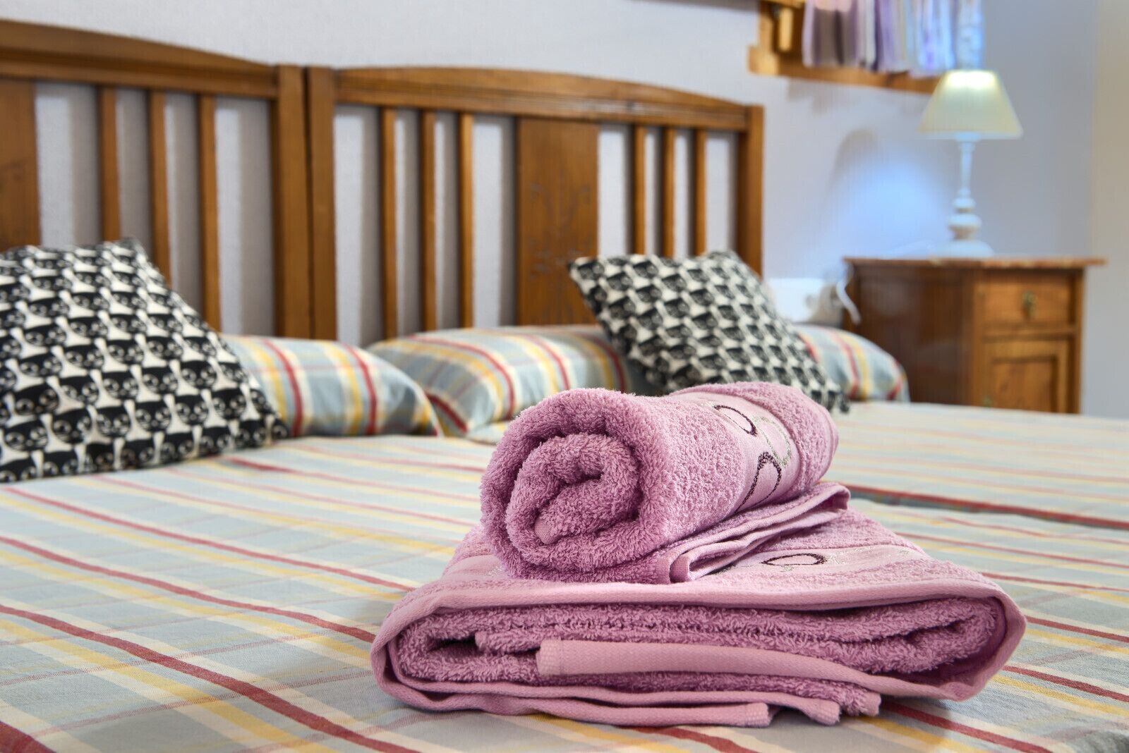 A neatly made bed with striped bedding, a wooden headboard, and patterned pillows.