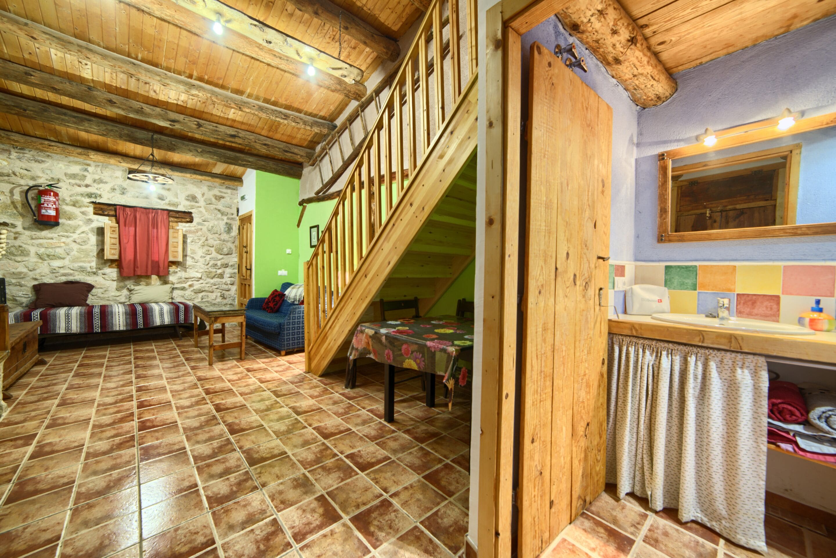 Un intérieur rustique avec un mur en pierre, un escalier en bois et un coin repas.